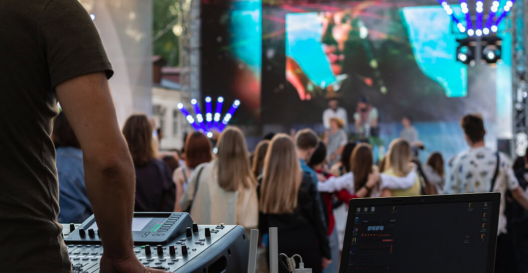 Outdoor concert featuring DJ and crowd enjoying live music performance.